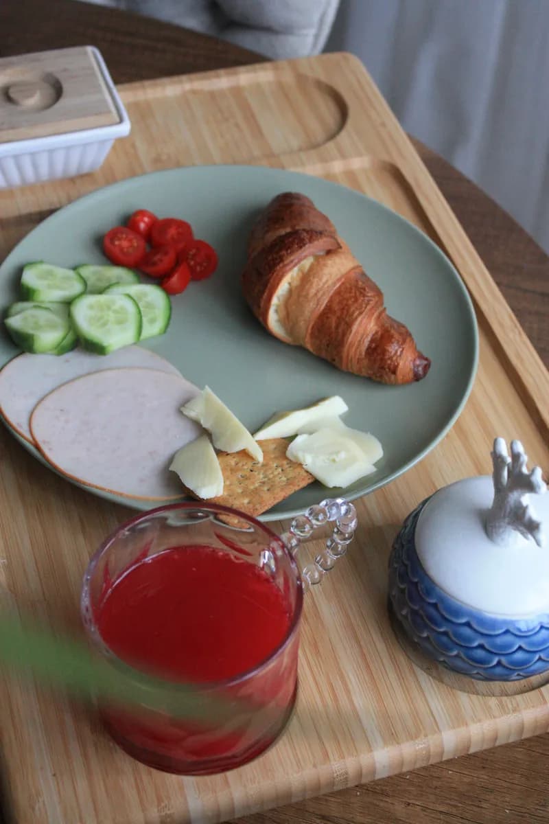 BookNoFees example image: Breakfast tray with a croissant, vegetables, and juice