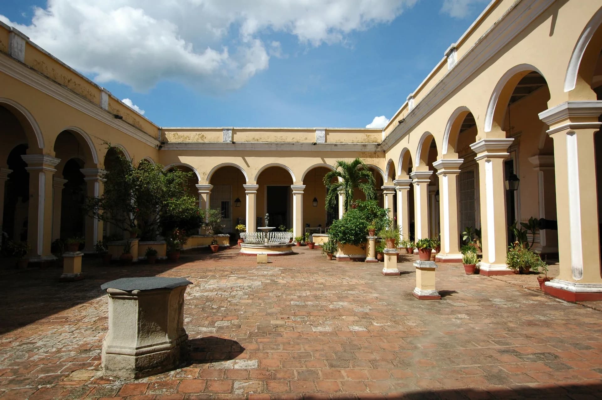 BookNoFees example image: Cuban courtyard with yellow arcades and plants