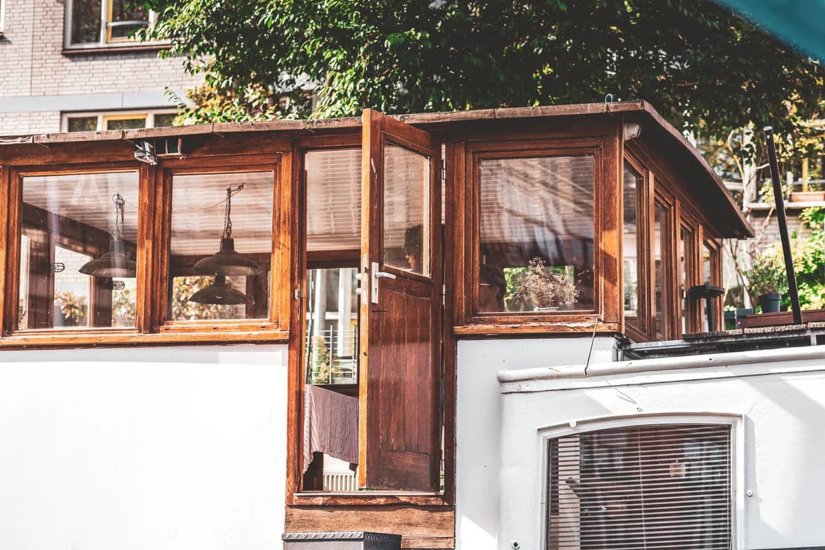 Imej contoh BookNoFees: rumah bot kayu dengan pintu terbuka di atas air tenang