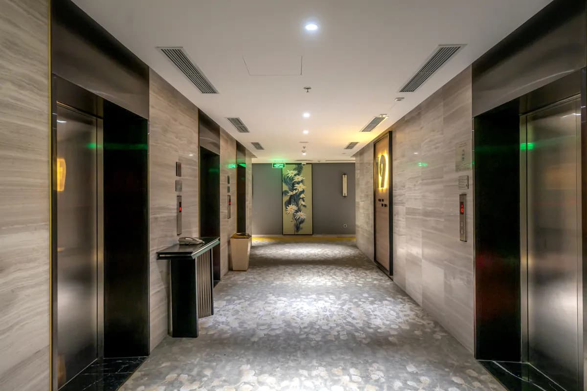 Imej contoh BookNoFees: Koridor hotel dengan lif dan karpet kelabu