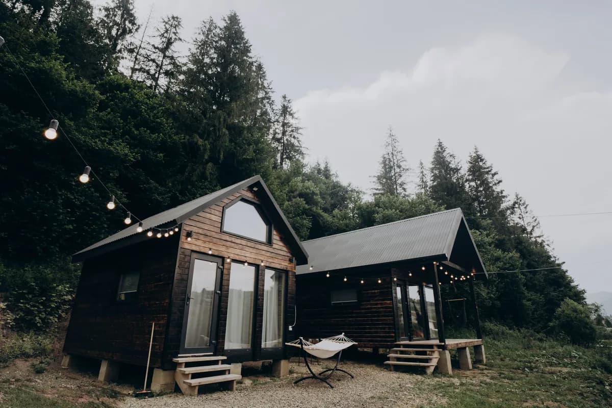 BookNoFees sample image: Small wooden cabins with string lights among the trees in the forest
