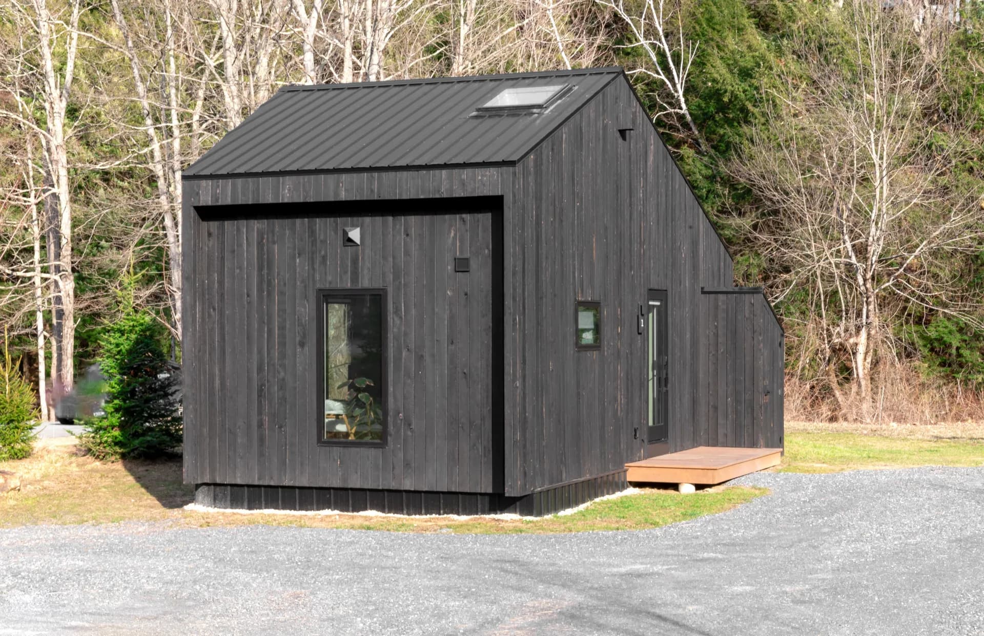 BookNoFees Sample Image: Small black wooden house with a skylight at the edge of the forest