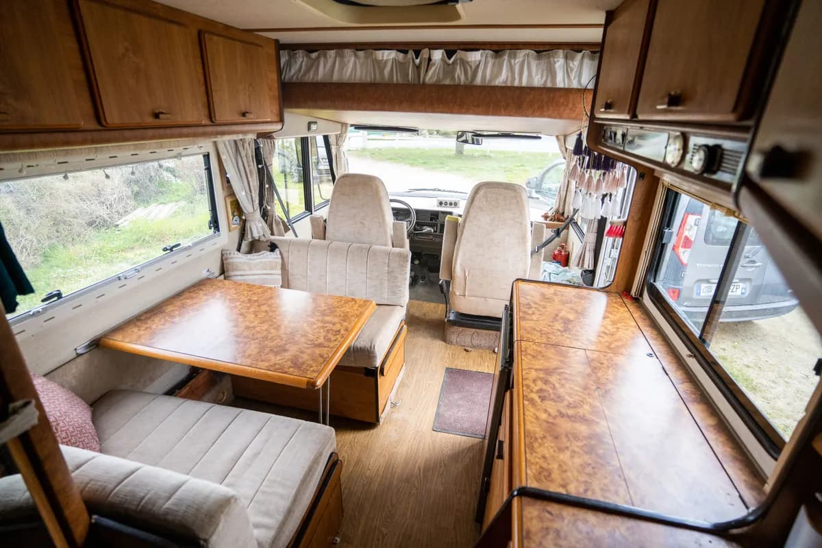 Imej contoh BookNoFees: dalaman motorhome dengan dapur, meja dan bangku berlapik