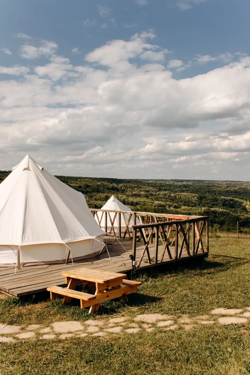 BookNoFees example image: Glamping tents set up on wooden platforms in an open landscape