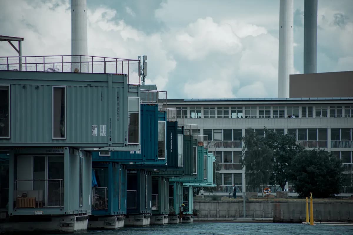 BookNoFees example image: Colorful container-style apartment buildings with a pier by the water