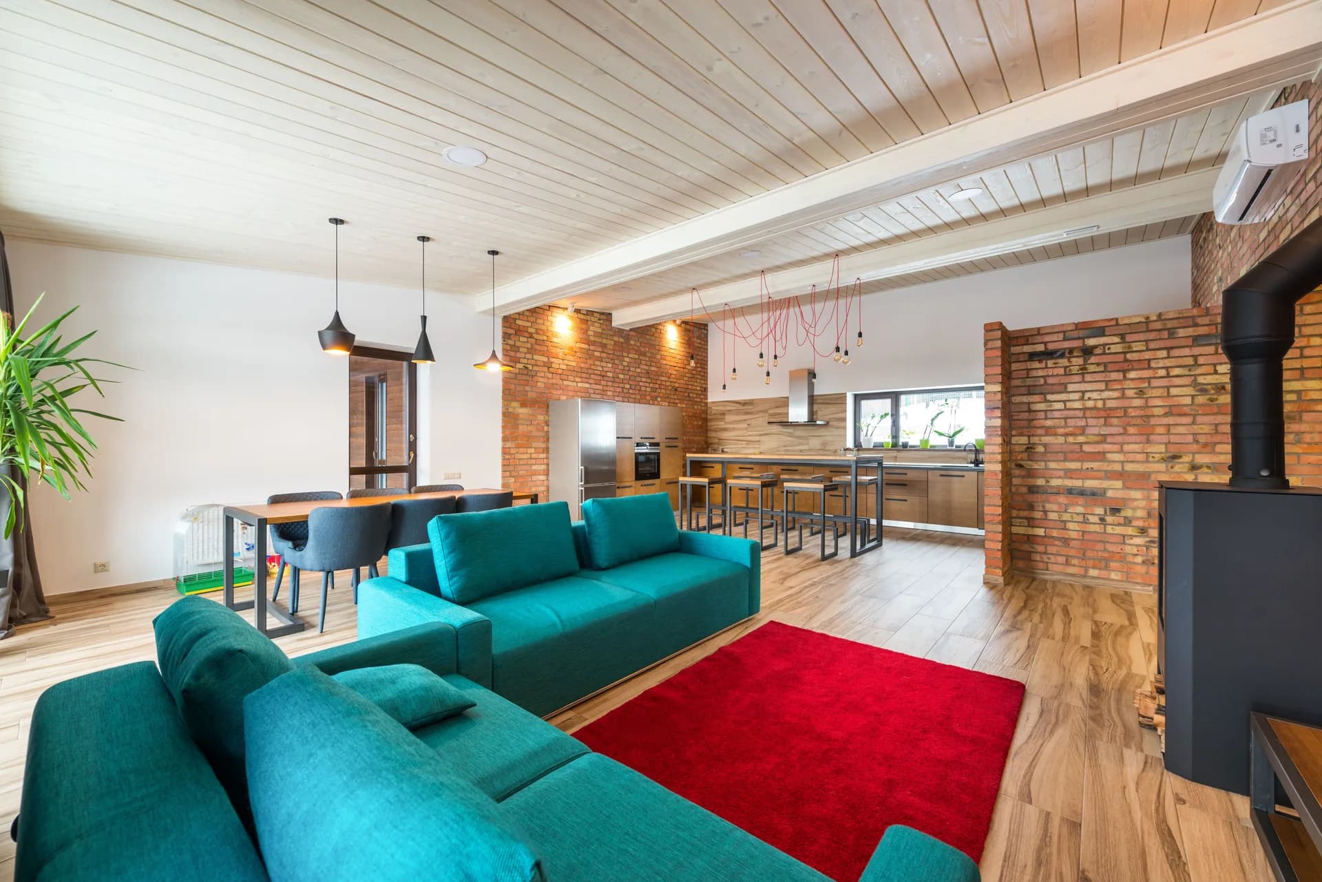 BookNoFees sample image: Open-concept living space with a turquoise sofa, brick wall, and kitchen