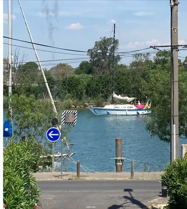 BookNoFees vacation rental in Agde, Occitania, France – Street view with river, sailboat, and road signs