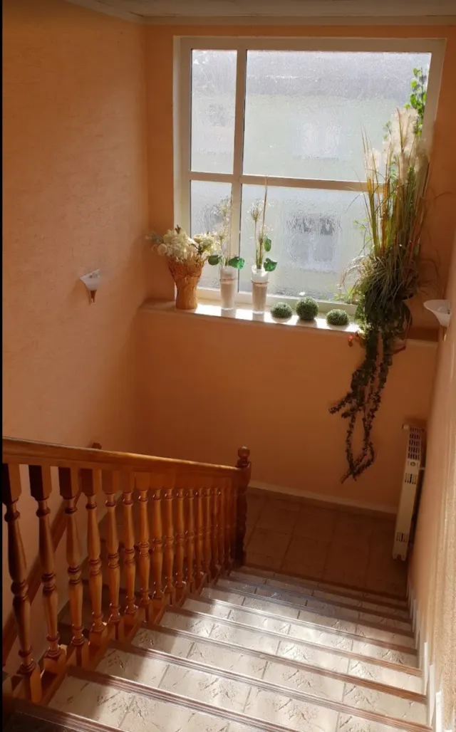 BookNoFees vacation rental in Schönfeld, Saxony, Germany – Staircase with wooden railing and window with potted plants on sill