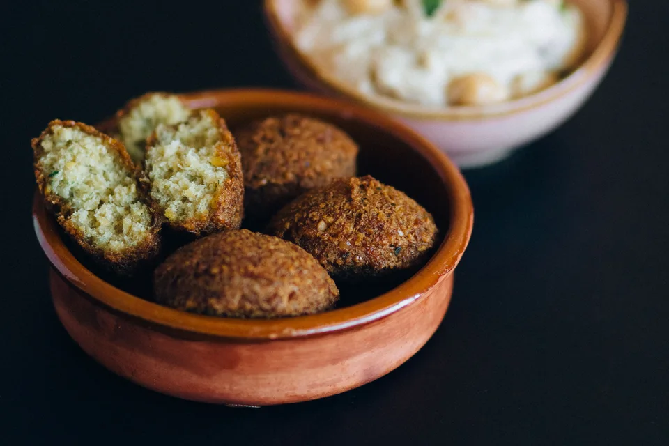 BookNoFees: Contoh foto: Bola falafel, termasuk satu keping yang dibelah, dalam mangkuk dengan hummus di belakangnya