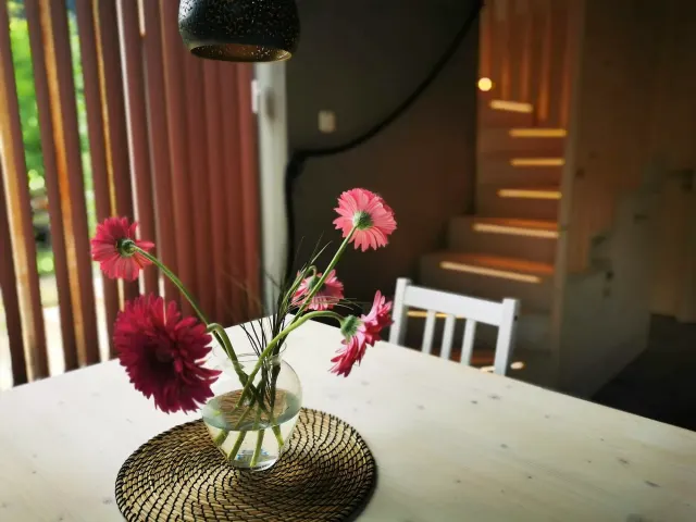 BookNoFees: homestay di Hieflau, Styria, Austria – Ruang makan dengan meja putih, pasu bunga merah jambu, dan tangga kayu