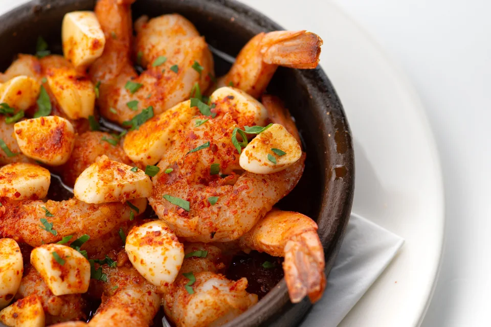 Contoh foto: Udang bawang putih dihias dengan herba cincang dalam mangkuk hitam di atas pinggan putih