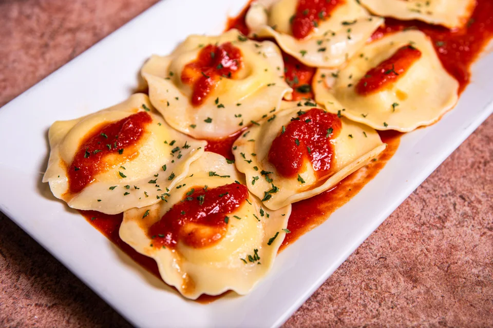 Contoh foto: Ravioli di atas sos tomato dan herba di atas pinggan putih